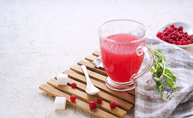 Traditional Russian hot drink red currant jelly or kissel in a transparent glass cup on a light concrete background. Drink recipes. Berry drinks.