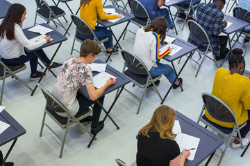 High school students taking exam at desks in classroom