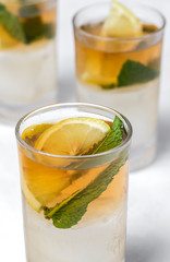 tea with ice, mint and lemon wedges on white table