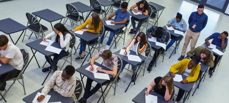 Instructor supervising high school students taking exam at desks