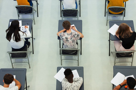 Overhead view high school students taking exam at desks in classroom