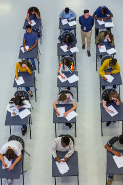 High school teacher supervising students taking exam at desks