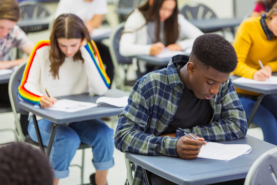 Focused high school boy student taking exam at desk in classroom