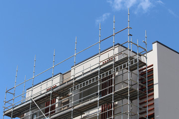 Steel scaffolding platforms on a modern muti story apartment building construction site. Blue sky background
