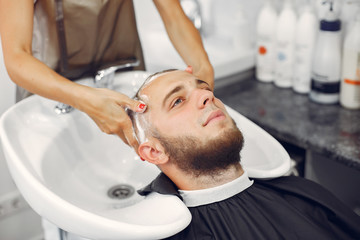 Man with a beard. Hairdresser with a client. Woman washing man's head