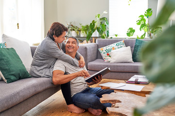 Affectionate mature couple reading and talking in living room