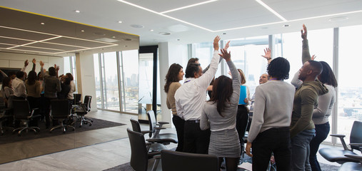 Business people cheering in huddle in office meeting