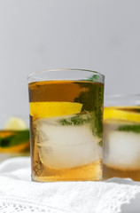 tea with ice, mint and lemon wedges on white table
