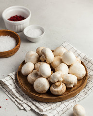  Fresh champignon porcini mushrooms on a wooden plate, spices in bowls. Food for vegetarians. Copy space