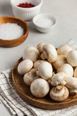  Fresh champignon porcini mushrooms on a wooden plate, spices in bowls. Food for vegetarians. Copy space