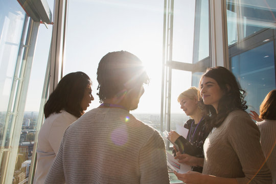 Business people talking at sunny office window