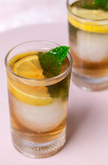 tea with ice, mint and lemon wedges on white table