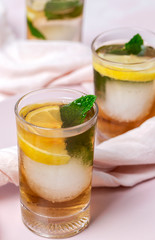 tea with ice, mint and lemon wedges on white table