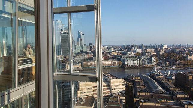 Businesswoman using smart phone at urban highrise office window