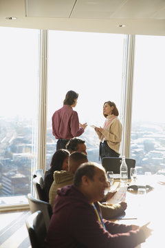 Business people talking at sunny highrise office window