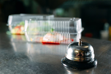 food delivery. distribution table in a restaurant with a metal bell. food in plastic containers. Panna cotta and vegetable salad in a plastic disposable containers.