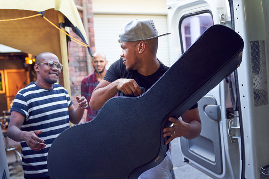 Musicians loading guitar case into van
