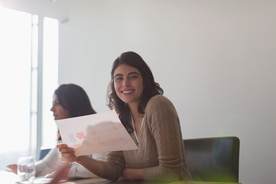 Portrait confident happy businesswoman with paperwork in office