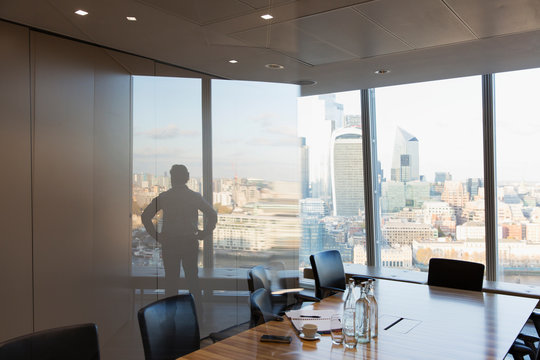 Silhouette businessman standing at urban highrise office window