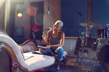 Smiling young woman writing song in recording studio