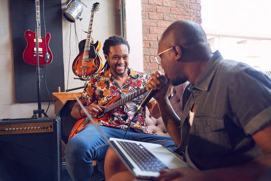 Happy male musicians practicing in recording studio
