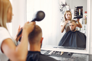 Man with a beard. Hairdresser with a client. Woman drying man's hair
