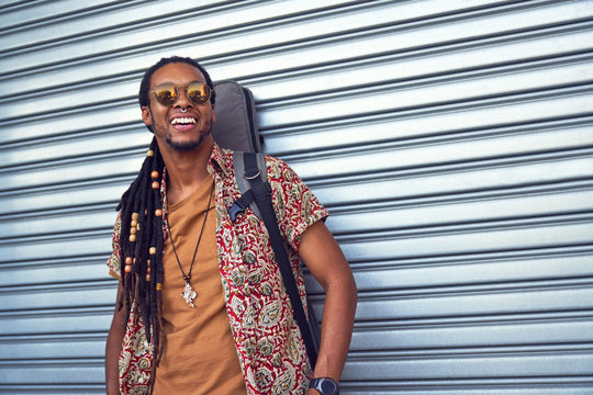 Portrait happy male musician with guitar case