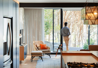 Thoughtful man standing at open patio door