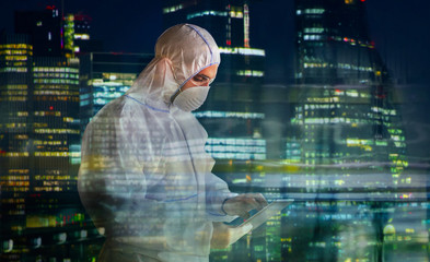 Male scientist in clean suit using digital tablet and working late