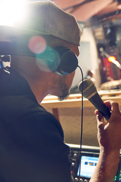 Male music producer with microphone in recording studio