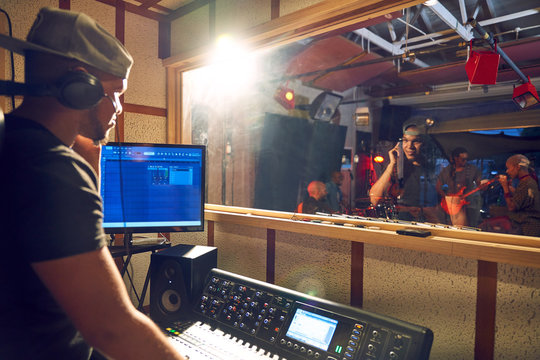 Male music producer at sound board in recording studio