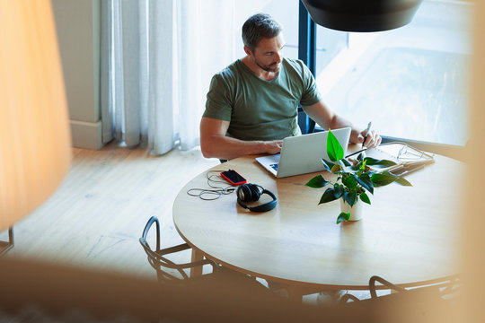Man using laptop, working from home at dining table