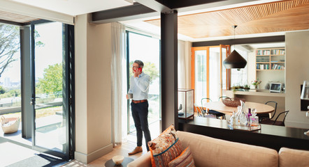 Man with coffee talking on smart phone in modern house