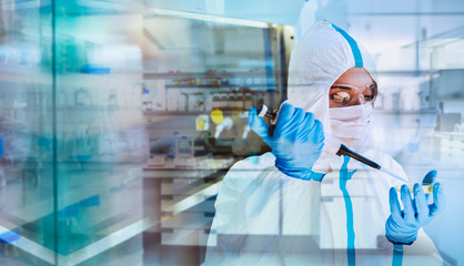 Female scientist in clean suit researching coronavirus in laboratory