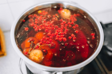 Cooking a delicious compote of apricot, apples, cherries, raspberries. Fresh fruits are boiled in boiling water in a metal pan on the stove. Photography, concept.