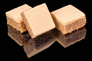 Tasty pieces of classic walnut cake Agnes with reflection, isolated on black background.