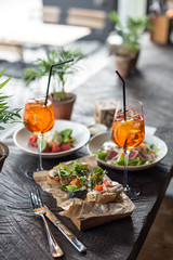 Bruschetta Sandwich, Salads and Aperol Spritz Cocktails. Assorted Appetizers. Summer Lunch