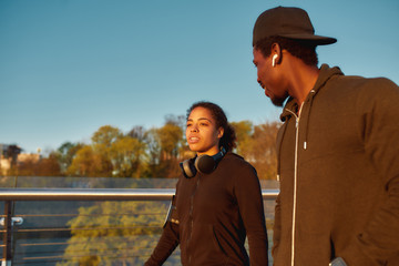 Jogging with partner. Young african female athlet talking with her boyfriend before morning jog. African sporty couple running together at sunrise