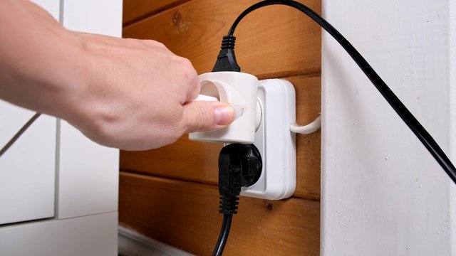 A Hand Pluging A Socket Into The Outlet, Overloaded Outlet With An Extension And Many Sockets Plugged In, Risk Of Fire And Short Circuit In A Wooden House