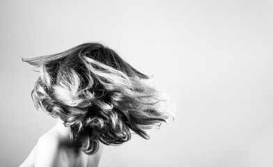 Toss and flip hair, back view. Black and white stock photo of a girl