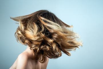 Young woman tossing her beautiful healthy thick hair. Concept of youth, freedom wellbeing,...