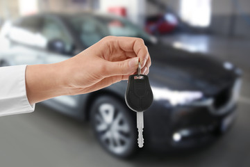 Woman with key near new automobile indoors, closeup