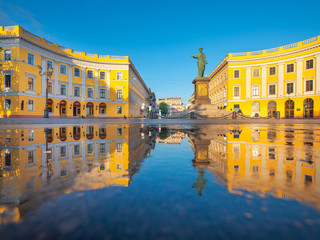 Fototapeta na wymiar morning around monument of city-founder of Odessa in Ukraine with golden light and blue sky with reflections and copy space