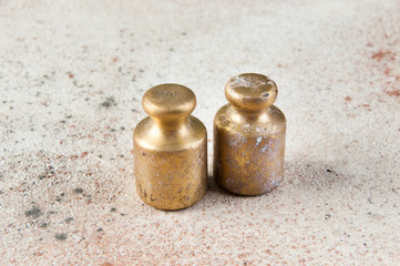 Two antique bronze weights for scales on concrete background.