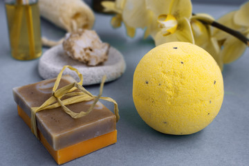 The accessories for spa treatments in salon  washcloth, bath bomb, soap, salt, yellow orchid flower on grey background.  Spa salon concept.