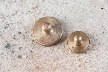 Two antique bronze weights for scales on concrete background.