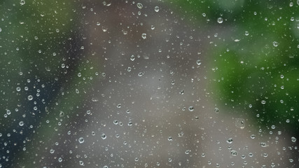 Raindrops on the window. Blur background of the street road and trees
