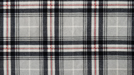 Grey, black and red checked, tartan pattern. Texture background. Macro shooting, closeup