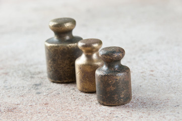 Fototapeta na wymiar Three antique bronze weights for scales on concrete background.