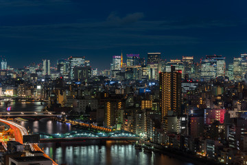 Fototapeta na wymiar Aerial night panoramic view of the Sumida river bridges and higways light-up with the skyscrapers of Tokyo.